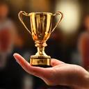 Una mano che tiene un trofeo d'oro stilizzato, con uno sfondo sfocato di una folla che applaude, simboleggiando il successo e il riconoscimento di Bosco Sano.